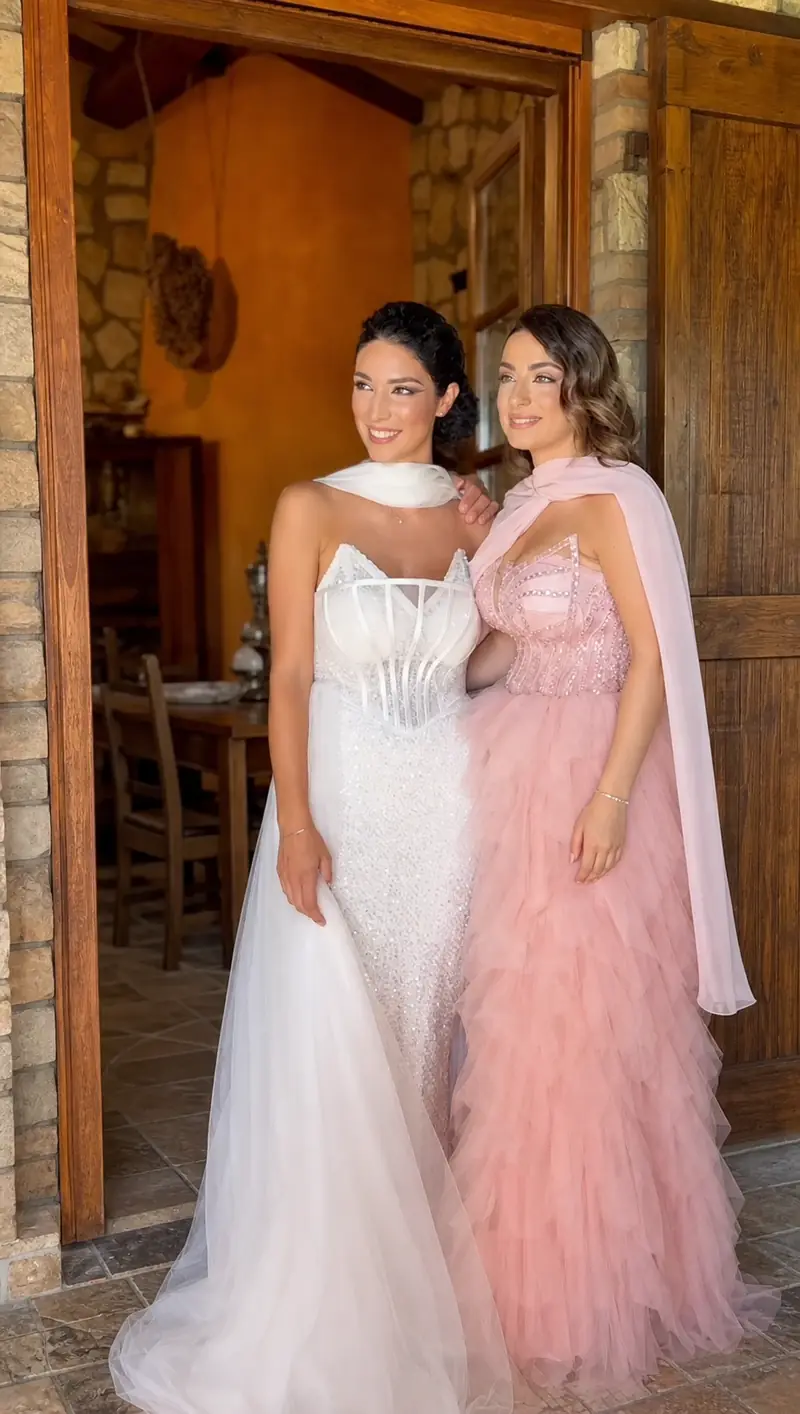Una sposa in abito bianco accanto a una donna in abito rosa